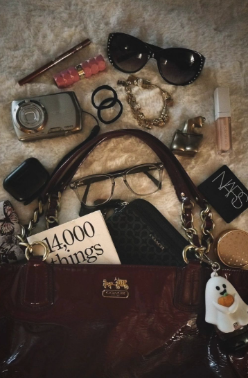 A collection of everyday objects arranged around a brown handbag